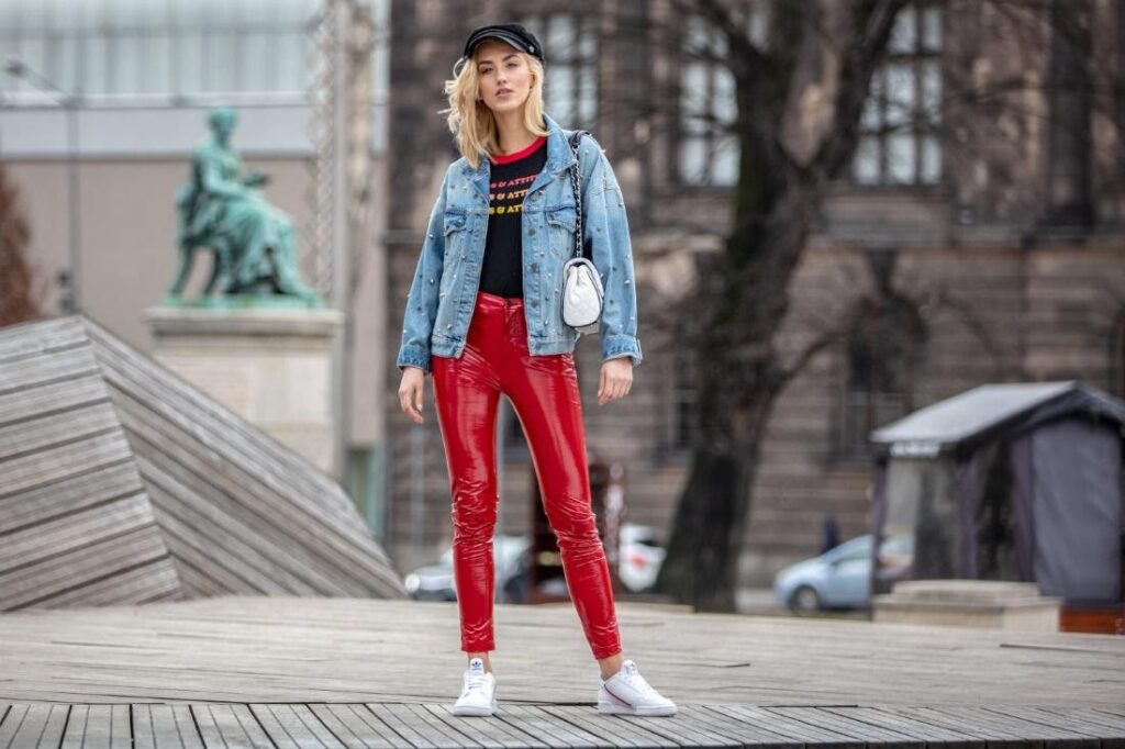 Egy modell piros nadrágban, fehér sneakerrel és farmerdzsekiben