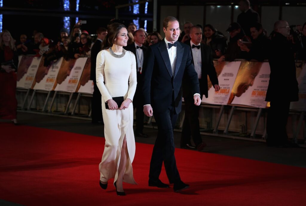 Kate Middleton egy fehér ruhában és fekete táskával