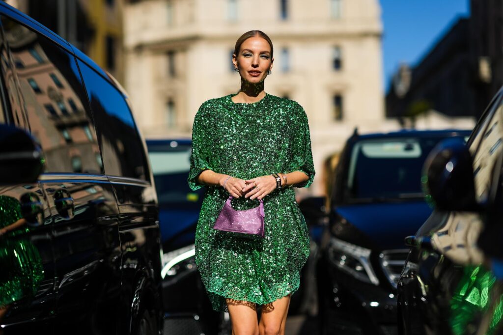 Egy modell zöld, csillogó ruhában és pasztelles táskával