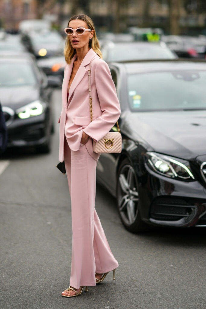 Rózsaszín kosztümöt és magassarkú szandált viselő nő